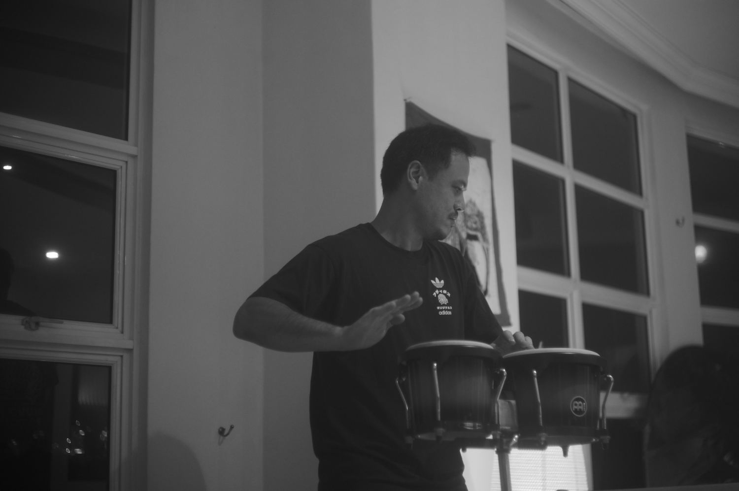 A musician playing hand drums beside a window