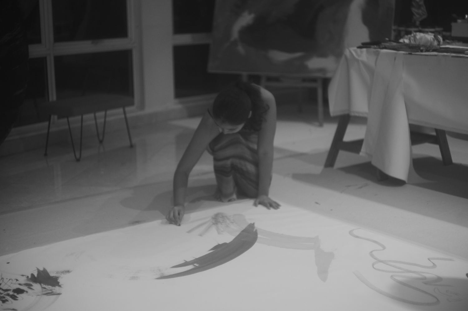 A child painting alone on the large floor canvas