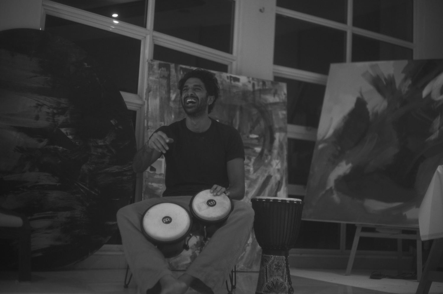 A drummer mid-laugh, surrounded by canvases